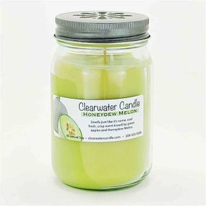 May include: A green glass jar candle with a silver lid. The candle is labeled "Clearwater Candle Honeydew Melon" and has a description that reads "Smells just like it's name, cool fresh, crisp scent kissed by green apples and Honeydew Melon. All natural Soy - clearwatercandle.com - 208-501-9200".