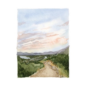 May include: A watercolor painting of a winding dirt path leading to a valley with a river and mountains in the distance. The sky is a soft blue with pink clouds.