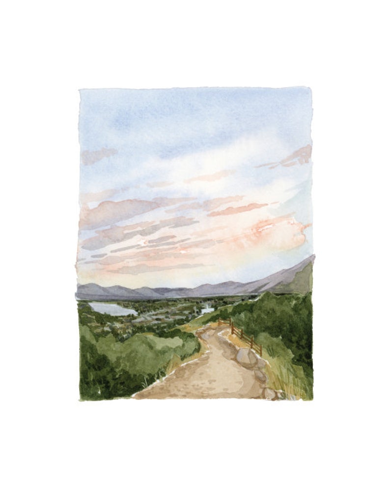 May include: A watercolor painting of a winding dirt path leading to a valley with a river and mountains in the distance. The sky is a soft blue with pink clouds.