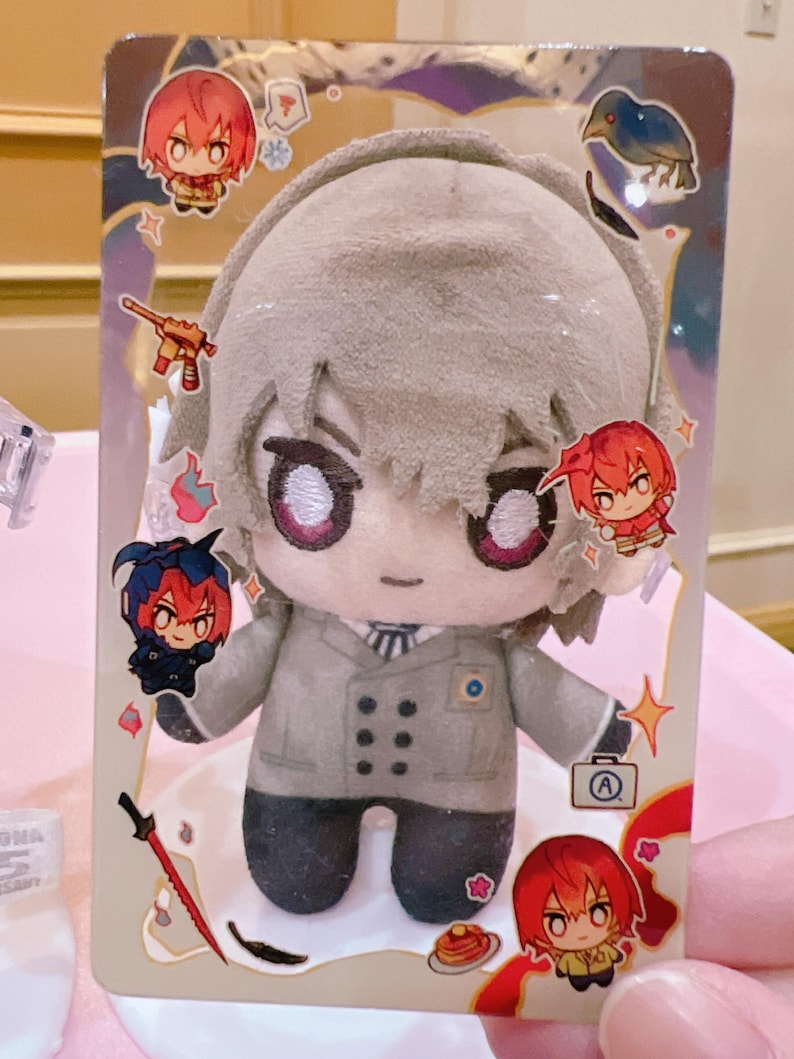 Puede incluir: Un juguete de peluche de un personaje con cabello gris, que lleva una chaqueta gris con botones negros y una insignia azul. El juguete est&aacute; rodeado de ilustraciones de personajes m&aacute;s peque&ntilde;os sobre un fondo blanco.