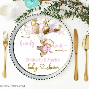 May include: A white baby shower plate with a pink and gold teddy bear holding balloons. The text on the plate reads "We can bearly wait to meet you Kimberly & Mark's baby shower".