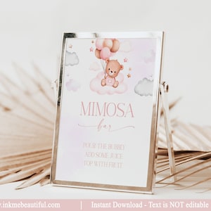Peut inclure: Une affiche imprimable de 8x10 pouces pour un bar à mimosa avec un fond aquarelle rose et blanc. Un ours en peluche brun tient des ballons roses et bruns et est assis sur un nuage. L'affiche indique "Bar à mimosa" et comprend des instructions pour faire un mimosa : "Versez le pétillant, ajoutez du jus, garnissez de fruits".