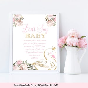 May include: A printable sign with a pink and gold floral design and a swan illustration. The sign says "Don't Say Baby" and includes instructions for a game. The text says "Please take a PIN and put it on your clothes. When you hear someone say "BABY" you can take one of their pins. Whoever has the most pins at the end will WIN!"