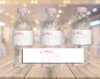 May include: Three clear water bottles with pink ribbon and bow labels that say "Alexis & Mark's Baby Shower".
