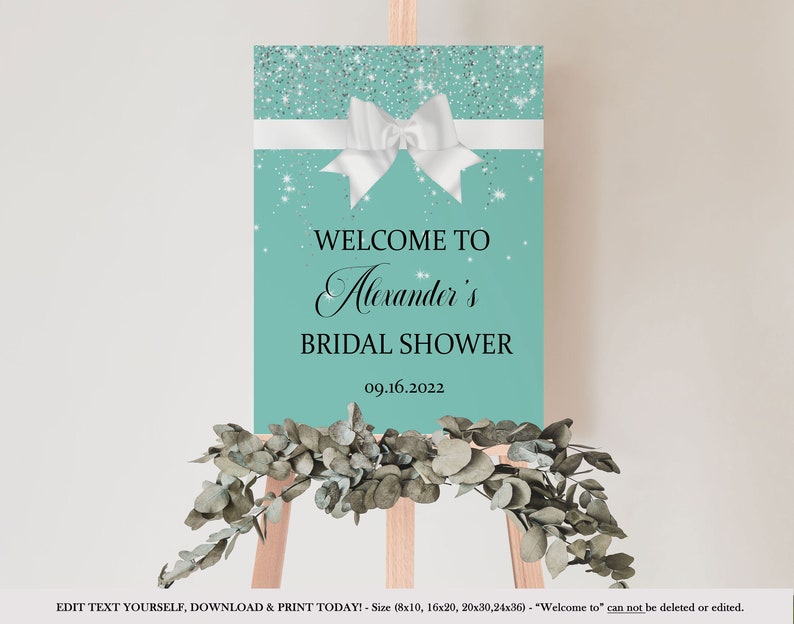 Op de afbeelding: Een turquoise blauwe bruiloftsshower welkomstbord met een witte strik en zilveren glitter. Het bord zegt "Welkom bij Alexander's Bridal Shower 09.16.2022".