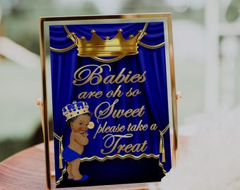 Puede incluir: Un cartel azul y dorado con una corona y un bebé con una corona. El cartel dice "Los bebés son tan dulces, por favor toma un dulce".