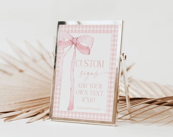 May include: A silver picture frame with a pink and white gingham border. The frame has a white background with a pink watercolor bow and the text "CUSTOM signs ADD YOUR OWN TEXT 8"x10" Unlimited Downloads".