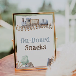 May include: A printable 8x10 sign with a watercolor illustration of a blue train on a track. The sign says "On-Board Snacks" in brown text.