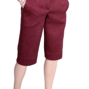 May include: A pair of maroon shorts with a button fly and a single button closure at the waist. The shorts have a straight leg and are made of a textured fabric.