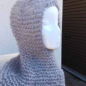 May include: A gray knitted balaclava with a fuzzy texture. The balaclava is shown on a white mannequin head.