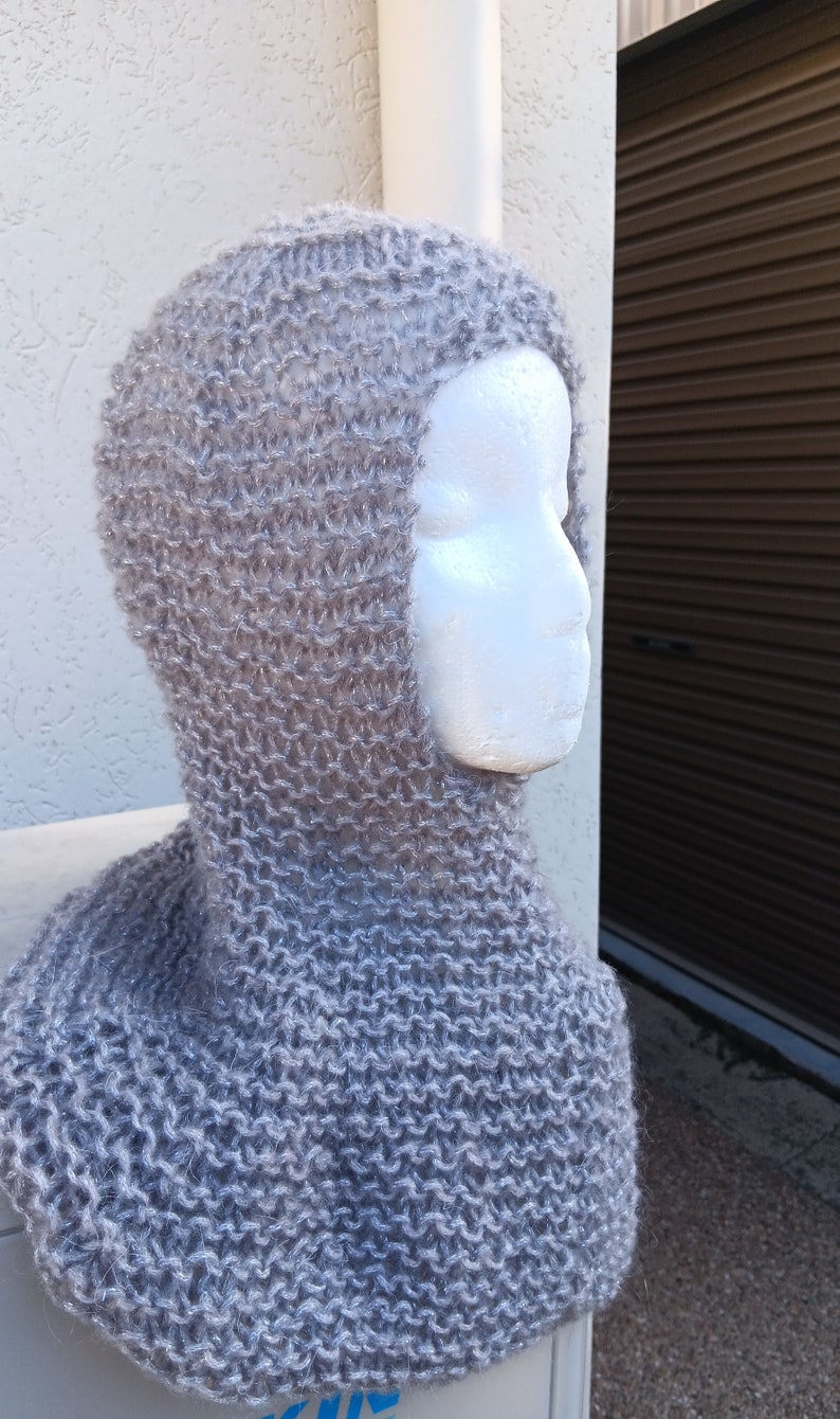 May include: A gray knitted balaclava with a fuzzy texture. The balaclava is shown on a white mannequin head.