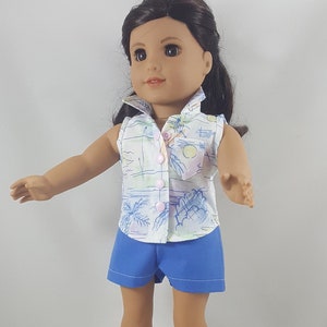 Peut inclure: Une poup&eacute;e portant une chemise blanche sans manches avec un imprim&eacute; palmier et un short bleu. La poup&eacute;e a les cheveux bruns et les yeux bruns et porte des sandales blanches.