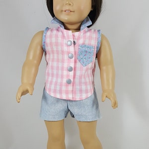 Peut inclure: Une poup&eacute;e portant une chemise sans manches en vichy rose et blanc avec une poche fleurie, un short en jean bleu et des sandales blanches &agrave; boucles.
