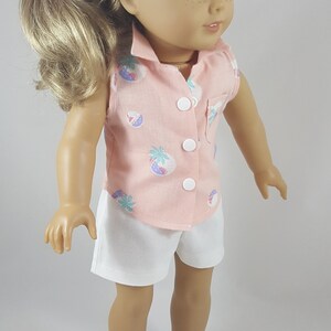 Peut inclure: Une poup&eacute;e portant une chemise rose sans manches avec un imprim&eacute; tropical et un short blanc. La poup&eacute;e a les cheveux blonds et les yeux bruns. La poup&eacute;e porte des sandales blanches avec des boucles brunes.