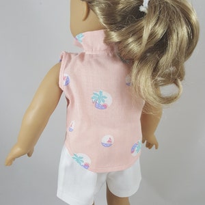 Peut inclure: Une poup&eacute;e portant une chemise rose sans manches avec un imprim&eacute; palmier et planche de surf et un short blanc. La poup&eacute;e a les cheveux blonds tir&eacute;s en arri&egrave;re en queue de cheval.