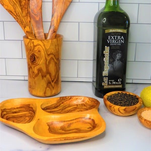 May include: Olive wood serving tray with three compartments, two olive wood bowls, one with black peppercorns, one with salt, and a bottle of La Espa&ntilde;ola Extra Virgin Olive Oil.