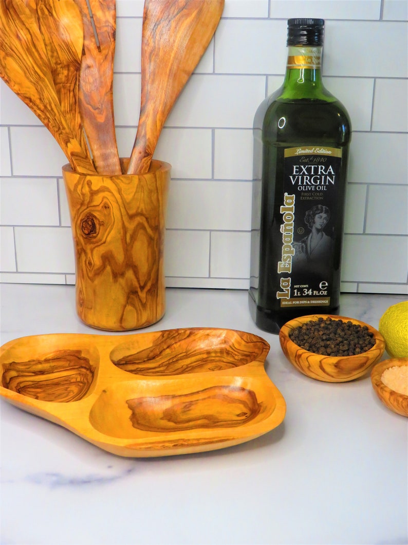 May include: Olive wood serving tray with three compartments, two olive wood bowls, one with black peppercorns, one with salt, and a bottle of La Espa&ntilde;ola Extra Virgin Olive Oil.