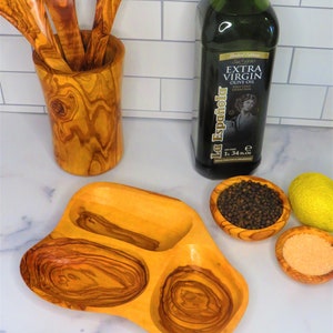 May include: A wooden serving dish with three compartments, perfect for serving olives, cheese, or other snacks. The dish is made of olive wood and has a natural, rustic finish.