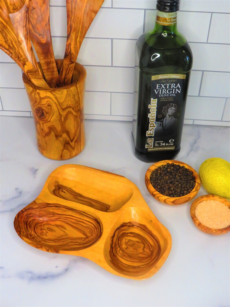 May include: A wooden serving dish with three compartments, perfect for serving olives, cheese, or other snacks. The dish is made of olive wood and has a natural, rustic finish.