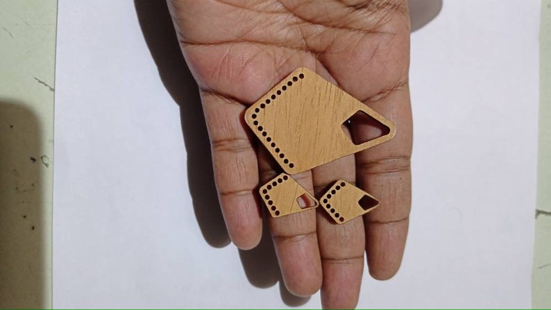 May include: Three wooden shapes with rounded edges and holes around the perimeter. The shapes are a large diamond, a smaller diamond, and a small triangle. The shapes are light brown and have a wood grain pattern.