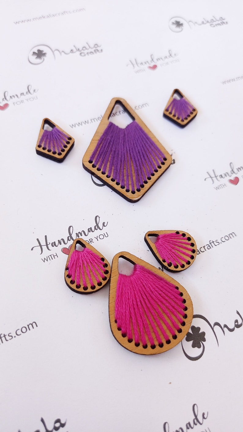 May include: Assortment of handmade wooden earrings with colorful thread embroidery. The earrings are in the shapes of a teardrop and a diamond. The text "Handmade with love for you" is visible on the white background.