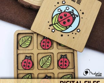 May include: A wooden tic-tac-toe game with a ladybug theme. The game board is made of wood and has nine squares. Each square has a ladybug or a leaf design. The game comes with a lid that has the words "Tic Tac Toe" written on it.