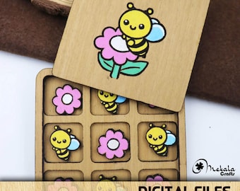 May include: A wooden tic-tac-toe game with a bee and flower design. The game board is open and shows the nine squares. Each square has a bee or flower design.