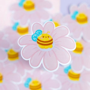 Adesivo simpatica ape seduta su un fiore rosa per decorare tutti i supporti