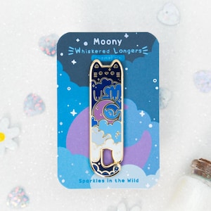 Könnte beinhalten: Eine blaue und weiße Emaille-Anstecknadel mit einer Cartoon-Katze mit einem Halbmond und Sternen im Hintergrund. Die Anstecknadel trägt die Aufschrift "Moony Whiskered Longers" und "Sparkles in the Wild".
