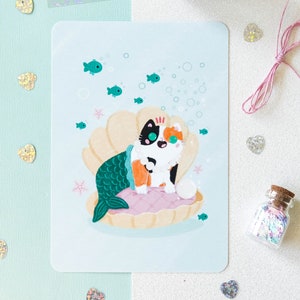 Illustration format carte A6 avec un chat calico sirène dans un coquillage avec une perle parfaite pour offrir ou décorer son intérieur