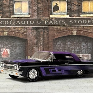 May include: A black and purple classic car with chrome wheels and purple side detailing. The car is parked in front of a brick building with the text "WALCOT AUTO & PARTS STORES" above the entrance.