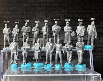 Puede incluir: Una colección de 17 figuritas grises pintadas de personas en varias poses, de pie sobre una superficie de plástico transparente. Cada figurita está numerada con un número de cuatro dígitos.