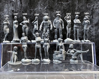May include: A collection of gray painted figurines, including a spaceman, women, and a man. The figurines are arranged on a clear display shelf with a white background.