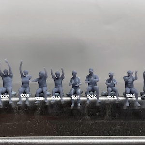 以下が含まれることがあります： さまざまなポーズをとった人の灰色の3Dプリントフィギュア10個セット。すべて腕を上げています。フィギュアは1236から1245まで番号が付けられています。