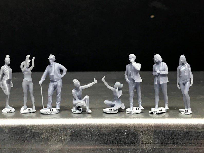May include: Eight gray figurines of people in various poses, standing on small bases labeled A1 through A8.