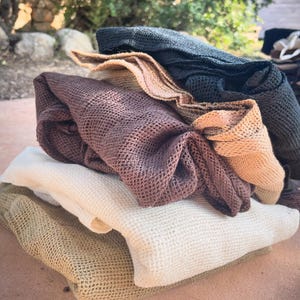 May include: A stack of four crocheted dishcloths in various shades of brown, beige, and black. The cloths are made of a soft, textured material and are perfect for cleaning and drying dishes.