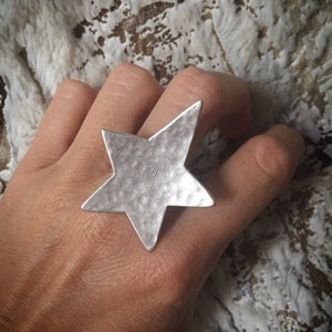 Puede incluir: Un anillo de plata en forma de estrella con una superficie texturizada.