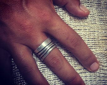 May include: A silver ring with multiple bands, worn on a finger.