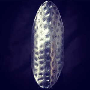May include: A silver ring with a hammered texture. The ring is oval shaped and has a smooth, polished finish.