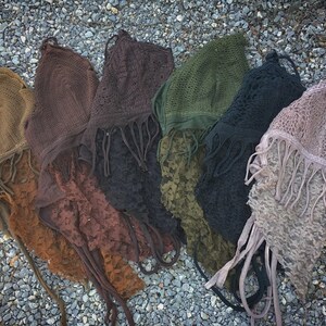 May include: Seven crocheted tops with fringe detailing in various colors, including brown, green, black, and purple.