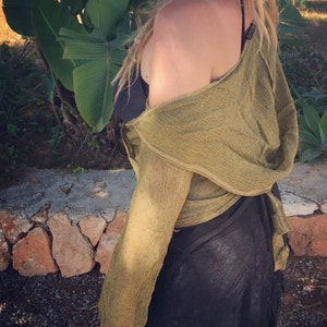 May include: A green, off-the-shoulder, long-sleeved, crocheted top with a loose, flowing fit. The top is tied at the waist and has a relaxed, bohemian style.