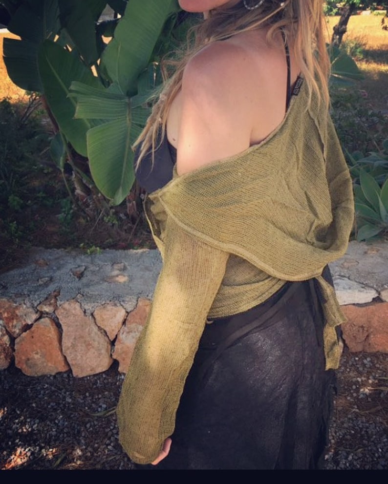 May include: A green, off-the-shoulder, long-sleeved, crocheted top with a loose, flowing fit. The top is tied at the waist and has a relaxed, bohemian style.