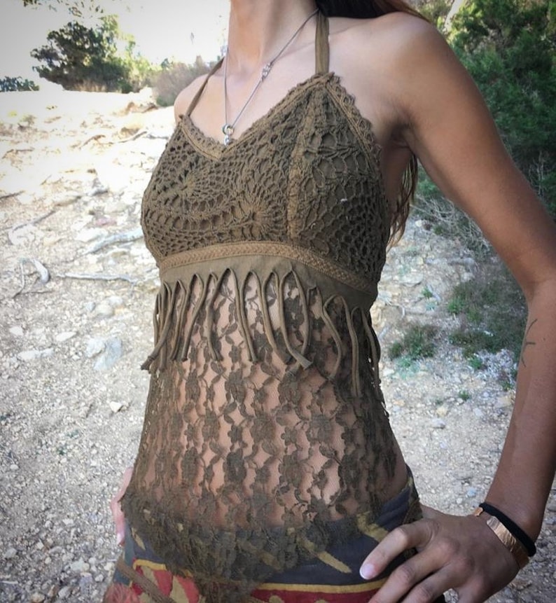 May include: A brown crochet top with a fringe trim and a sheer lace overlay. The top has a halter neck style and is made of a lightweight, breathable fabric.