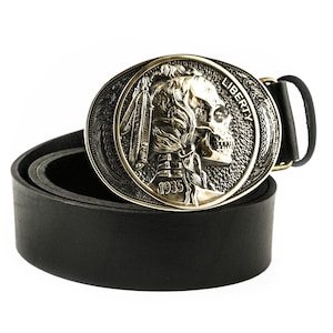 Peut inclure: Une ceinture en cuir noir avec une grande boucle en laiton ornée représentant un crâne avec une coiffe à plumes. La boucle est gravée des mots "LIBERTY" et "1935".