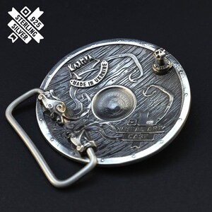 Puede incluir: Hebilla de cintur&oacute;n de plata con un dise&ntilde;o detallado de un escudo con un drag&oacute;n y el texto "Karmia Made in Ukraine Metal Art Cast".