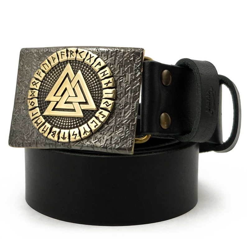 Peut inclure: Ceinture en cuir noir avec une boucle rectangulaire orn&eacute;e d'un symbole Valknut dor&eacute; entour&eacute; de runes. La boucle pr&eacute;sente un fond textur&eacute; gris fonc&eacute;.