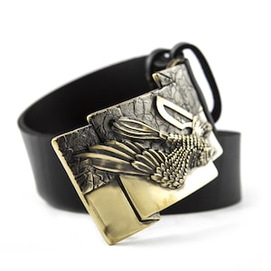 May include: A black leather belt with a gold-toned buckle featuring a detailed eagle design.