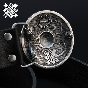 Puede incluir: Una hebilla de cintur&oacute;n de plata con un dise&ntilde;o detallado de un escudo con un drag&oacute;n y el texto "Metal Art Cast" y "Made in Ukraine".