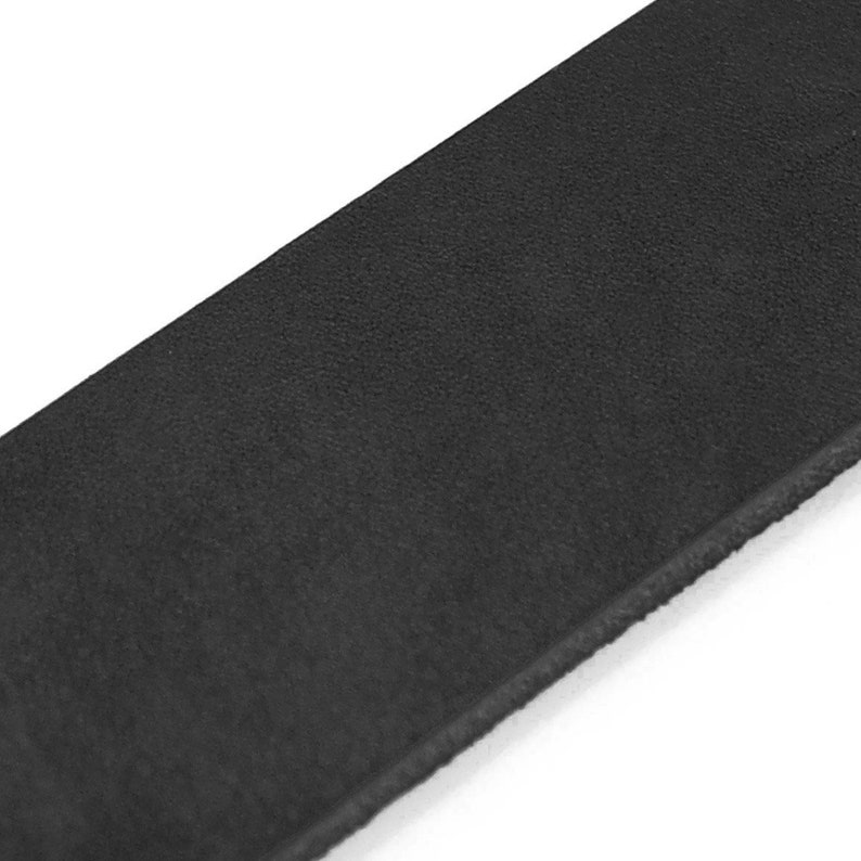Peut inclure: Gros plan d'une ceinture en cuir noir. La ceinture a une surface textur&eacute;e et un bord droit. L'image est sur fond blanc.