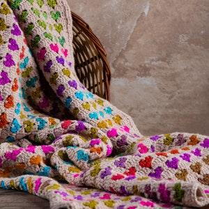 crochet heart blanket pattern with hearts in rainbow colors made with variegated yarn and beige yarn as the base color of the blanket.